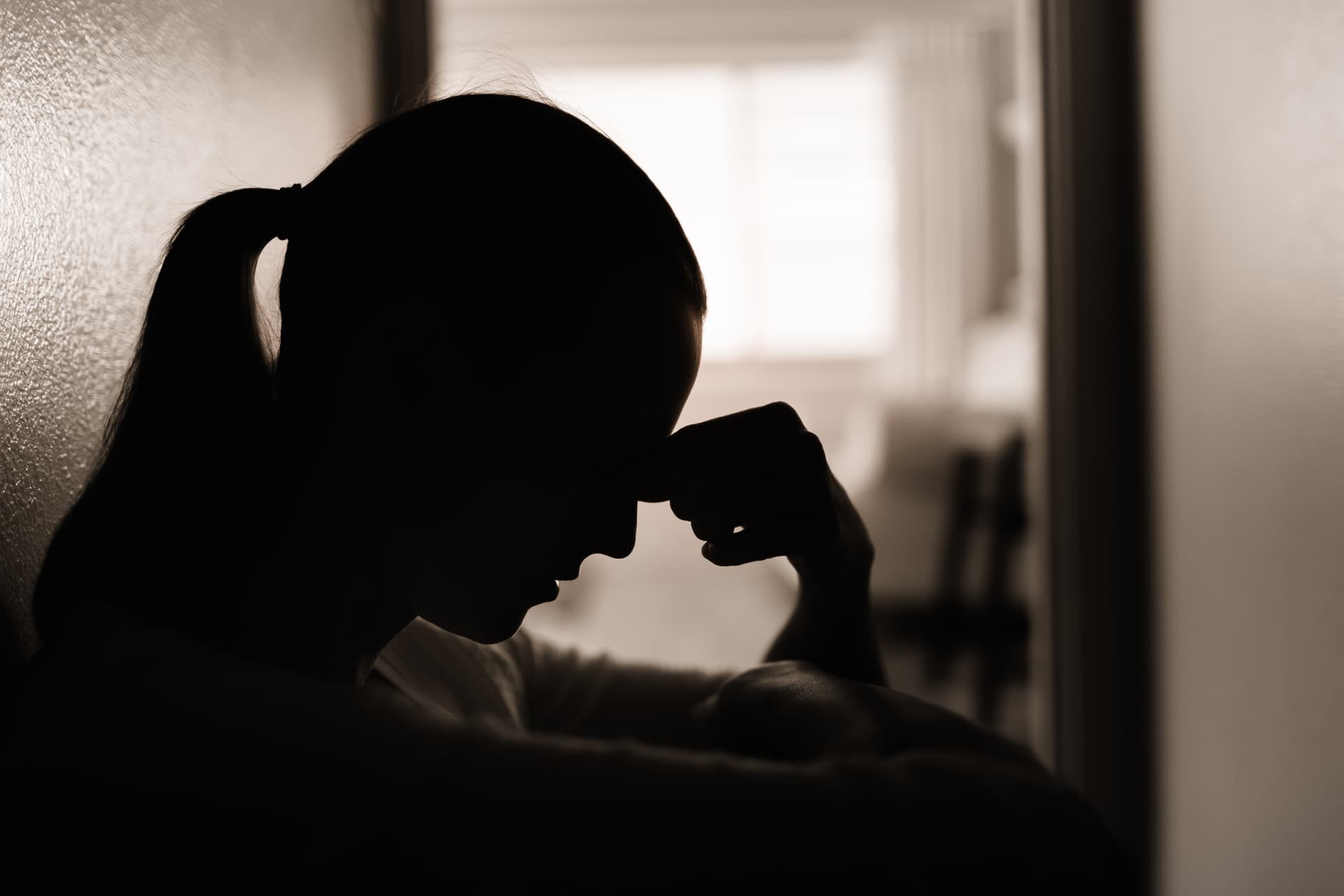 Silhouette of a person resting their head on their hand in grief