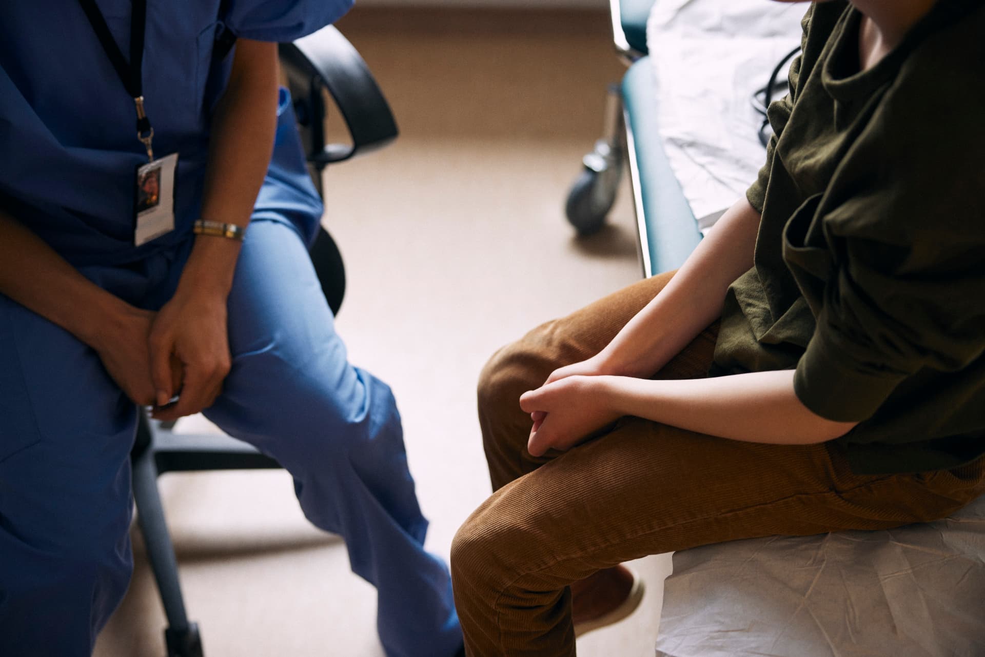 A patient sitting on a hospital bed speaking with a nurse